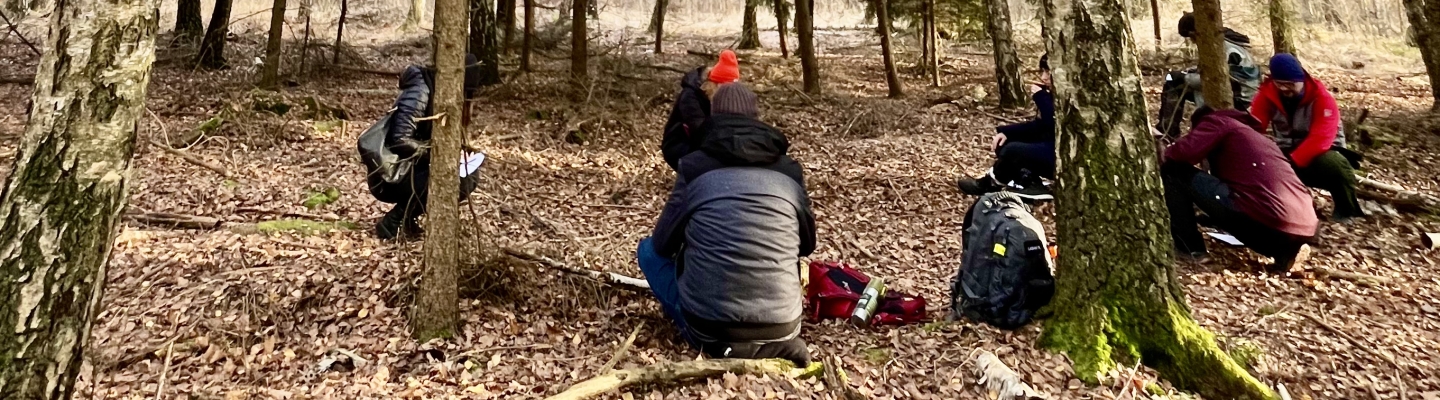 Osoby stojące w lesie między drzewami podczas kąpieli leśnej (c) Łukasz Derkacz