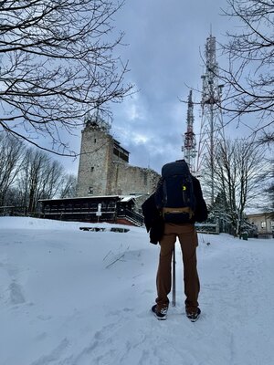 Osoba stojąca w zimie na tle ruin schroniska na Chełmcu (c) Łukasz Derkacz
